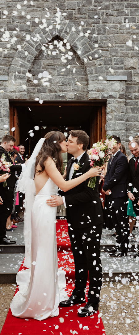 Couple kiss on their wedding day outside chapel at ballyseede castle hotel