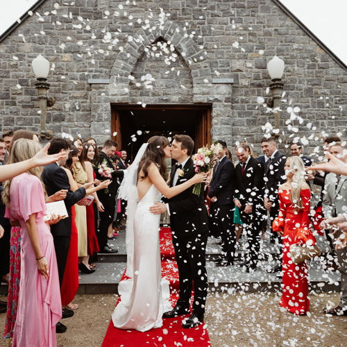 Couple kiss on their wedding day outside chapel at ballyseede castle hotel
