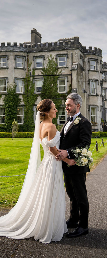 Couple embrace outside ballyseede castle wedding venue in kerry