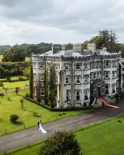 Couple embrace on wedding day with aerial view of ballyseede castle