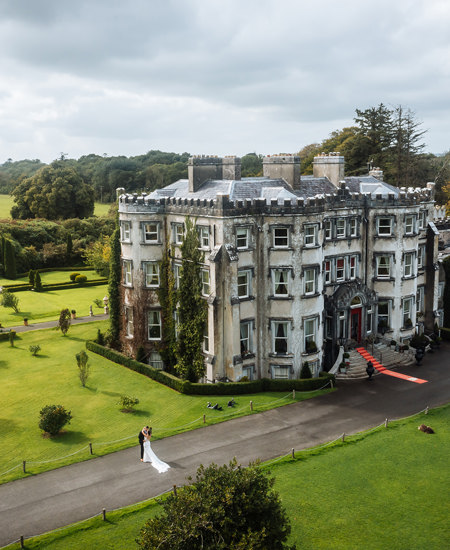 Couple embrace on wedding day with aerial view of ballyseede castle