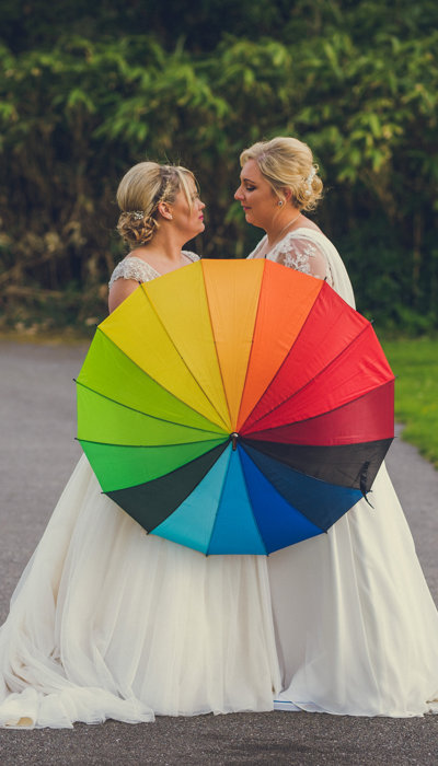Brides holding a rainbow umbrella on their wedding day at ballyseede castle
